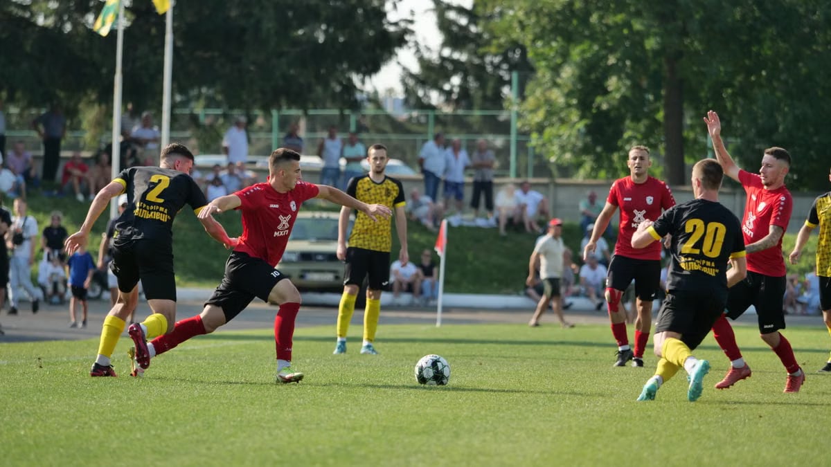 Dynamic action during a football match with teams in black and red jerseys.